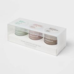 two jars of body scrubs in a white box on a white surface with the lid open