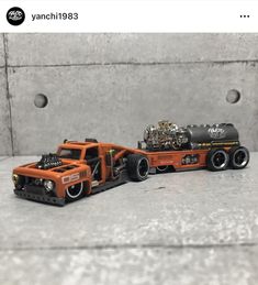 two toy trucks are shown on the table next to each other, one is orange and the other is black