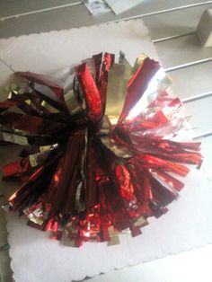 a red and gold tinsel pom - poms on top of a piece of paper