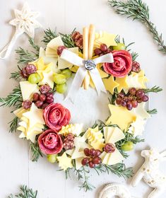 a wreath made out of fruit and flowers on a white surface with other decorations around it