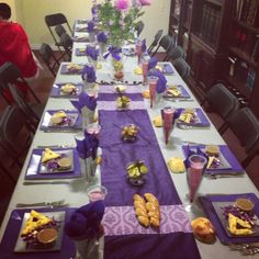 a long table is set with purple place mats