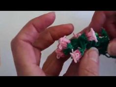 two hands are holding small pieces of crocheted fabric with pink and green flowers on them