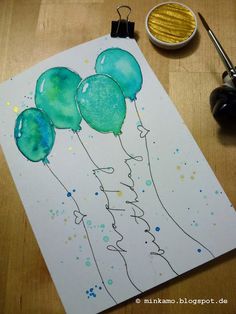 a painting with balloons on it next to a paintbrush and watercolor pencils