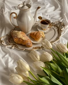 two croissants on a plate next to a cup and saucer with flowers