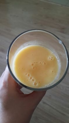 a hand holding a glass with orange juice in it