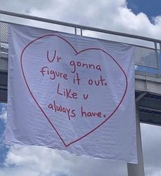 a white sign hanging from the side of a bridge