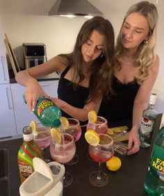 two women are making drinks in the kitchen