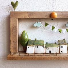 a wooden frame with some little houses on it and an orange hanging from the wall