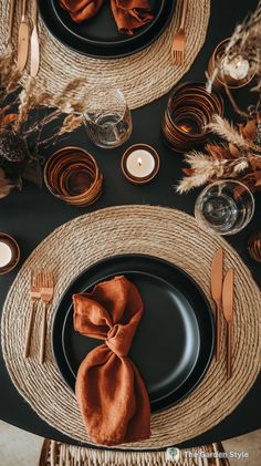 a place setting with black plates and orange napkins