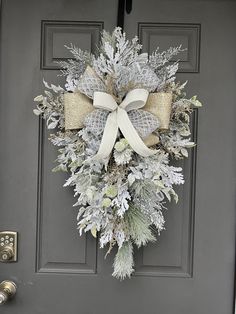 a wreath on the front door is adorned with white and gold ribbon, pine cones and evergreens