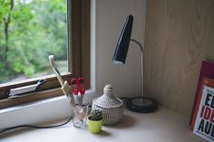 a desk with scissors and other office supplies on it next to a window sill