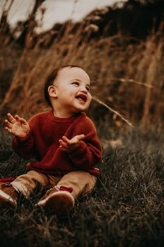 a baby sitting in the grass laughing