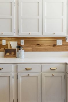 a kitchen with white cabinets and wood accents on the backsplash is seen in this image