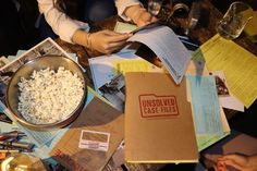 a table topped with lots of papers and boxes filled with food next to a bowl of popcorn