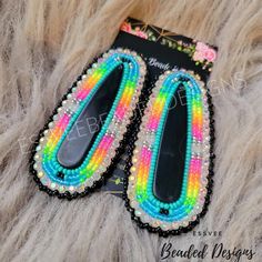 a pair of rainbow colored beaded shoes on top of a furry animal fur background