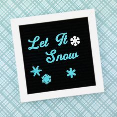 the words let it snow are written in blue on a black and white photo frame