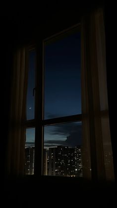 a window with the view of city lights at night