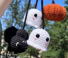 three crocheted halloween decorations hanging from a car's dashboard window, with eyes and noses on them