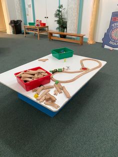 a toy train set sitting on top of a white table in a room with green carpet