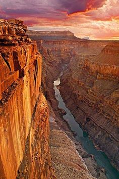 the sun is setting at the edge of a canyon with a river running through it