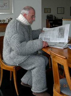 an old man sitting at a table reading a newspaper