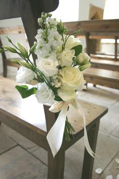 a bouquet of white flowers sitting on top of a wooden chair next to a bench