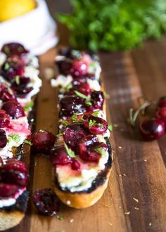 a wooden cutting board topped with bread covered in cheese and cranberry toppings