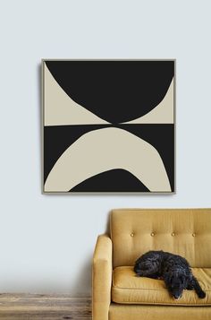 a black and white painting hanging on the wall next to a couch with a dog sleeping on it