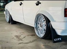 a white car with chrome rims parked in a garage