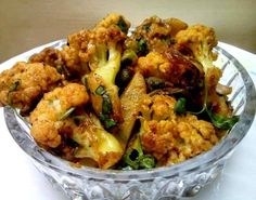 a glass bowl filled with fried vegetables on top of a white tablecloth covered table