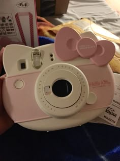 a pink and white camera sitting on top of a bed next to a teddy bear