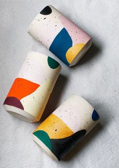 three colorful cups sitting on top of a white table