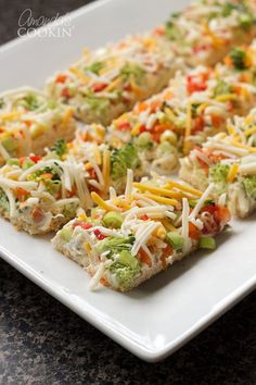 a white plate topped with crackers covered in cheese and veggie toppings