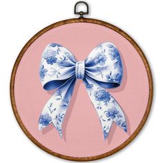 a blue and white bow hanging on a pink background in a round frame with wood trim