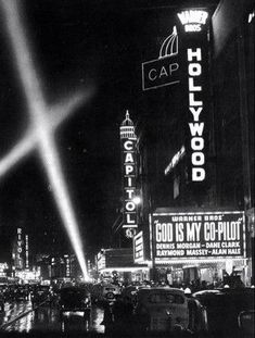 a black and white photo of the hollywood sign at night with cars parked in front