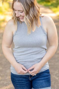 Elevate your style with the Tara Ribbed Tank in sophisticated grey! This tank combines fun and fashion with its micro ribbed texture and high neckline. Perfect for any occasion, it offers a comfortable fit that you'll love. Fabric Composition: 93% rayon, 7% spandex for a soft and stretchy feel.Fit: True to size.Model Sizing: Catherine and Tiffanee are wearing a small, and Lexi is in a 1XL. Upgrade your wardrobe with the Tara Ribbed Tank, a must-have versatile piece. Bath And Body Shop, Kids Graphic Tees, Jumpsuit Shorts Rompers, Leggings Kids, Ribbed Texture, Ribbed Tank, Short Leggings, Zip Up Sweater, Grey Women