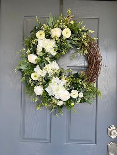 a wreath with white flowers and greenery hangs on the front door