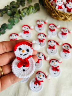 a hand holding a small crocheted snowman ornament in front of other ornaments