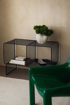 a green chair sitting next to a shelf with a potted plant on top of it