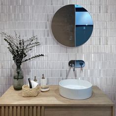 a bathroom with a sink, mirror and vase on the counter top in front of it