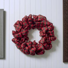 a red and black checkered wreath hanging on the wall next to a framed photo