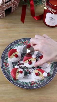 someone is decorating small christmas cookies on a plate