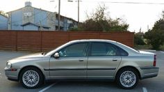 a silver car parked in a parking lot next to a wooden fence and brown building