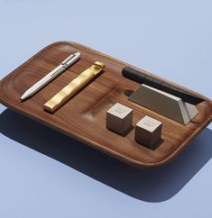 a wooden tray with some pens and other items on it, sitting on a blue surface