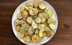 a white plate topped with fried zucchini on top of a wooden table