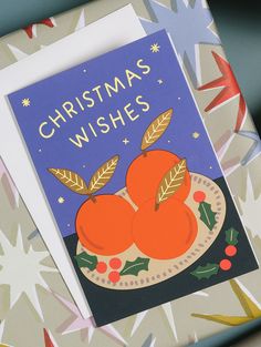 a christmas card with three oranges on a plate