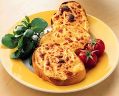 three pieces of bread with cheese and tomatoes on a yellow plate next to green leaves