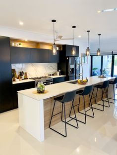 a modern kitchen with black and white cabinets, marble countertops and bar stools