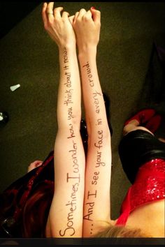 two people with their legs crossed and one has writing on the back of their arms