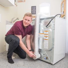 a man kneeling down next to an air conditioner